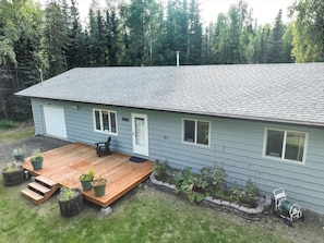 A single-story house with a wooden deck, a front door, and a small porch area.