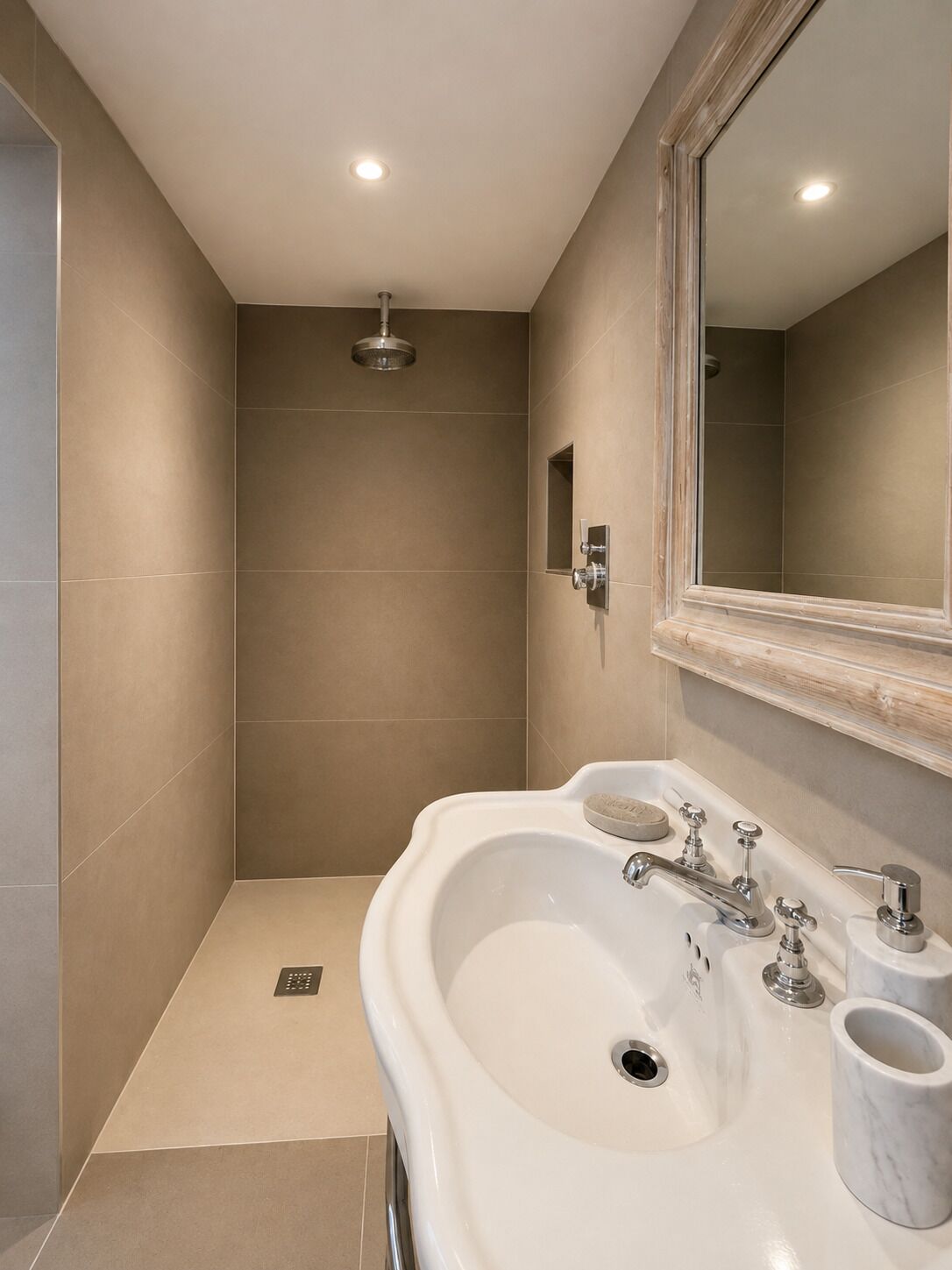 Un bagno moderno con un lavandino capiente, uno specchio e una doccia.