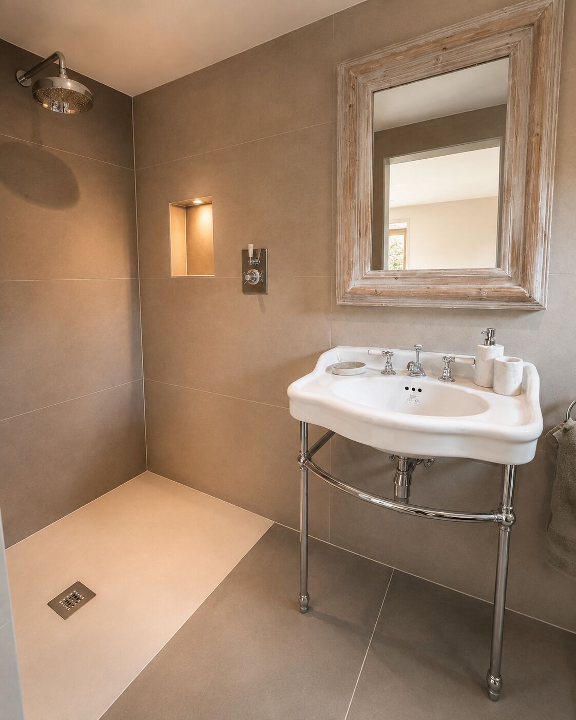 A bathroom with a white sink, a showerhead, and a mirror with a wooden frame.