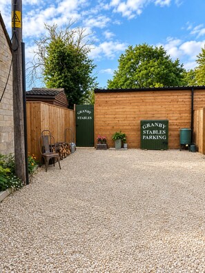 A gravel parking area with a wooden building labeled 'GRANBY STABLES PARKING' and a wooden fence.