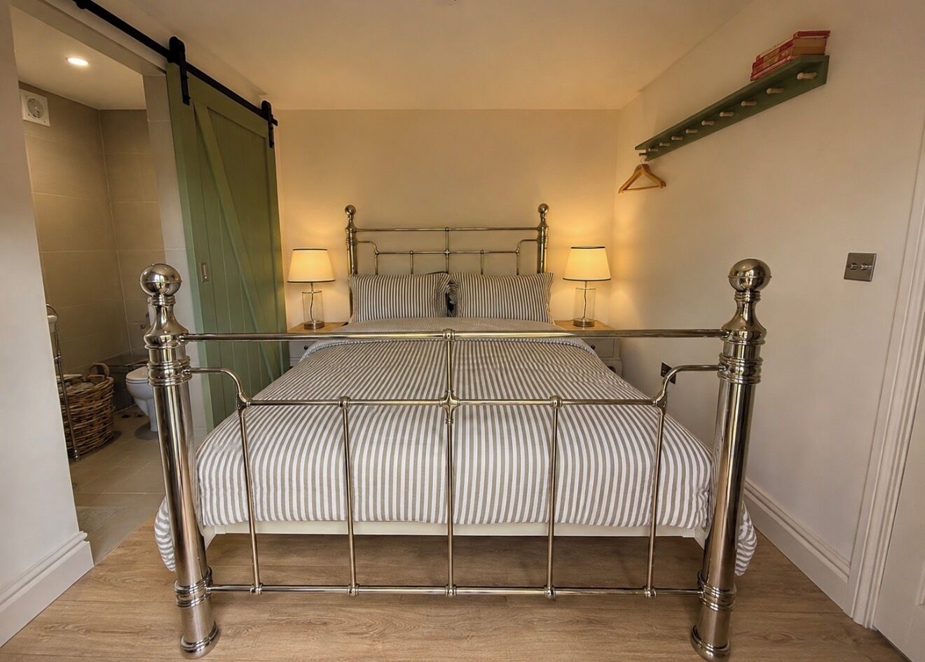 Un letto con struttura in metallo, due lampade sui comodini e una coperta a righe.