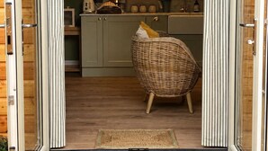 A sliding glass door entrance to a modern kitchen with a wicker chair and a star-shaped doormat.
