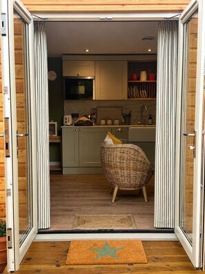 A sliding glass door entrance to a modern kitchen with a wicker chair and a star-shaped doormat.