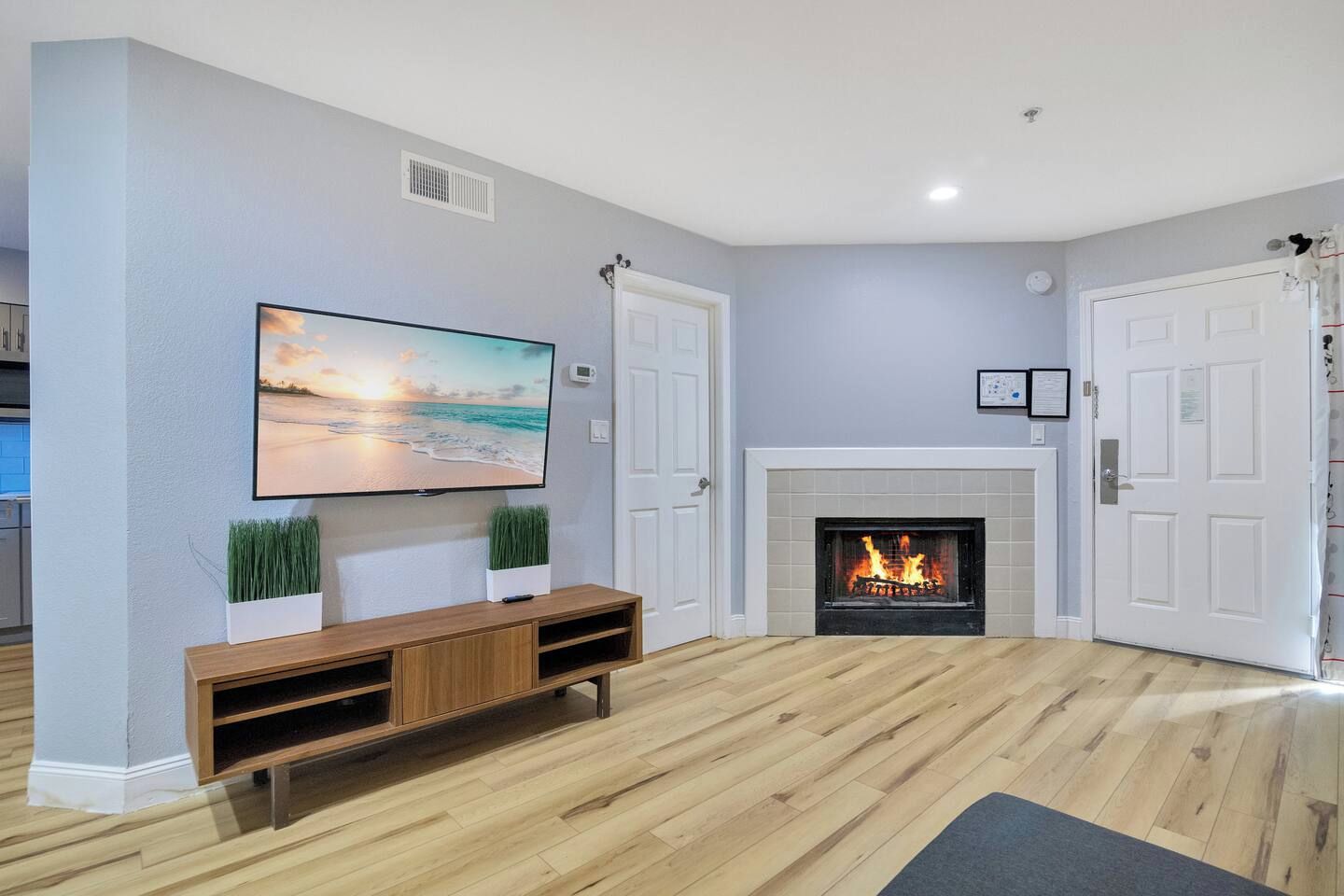 A living room with a flat-screen TV, a fireplace, and a wooden floor.