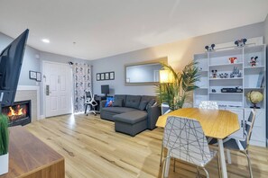 Un salon moderne avec une cheminée, un canapé, une table à manger avec des chaises et une bibliothèque contenant divers objets.