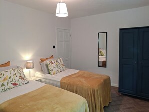 Ein Schlafzimmer mit zwei Betten, einem Nachttisch, einer Lampe, einem Spiegel und einem Kleiderschrank.
