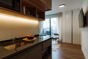 Een moderne keuken met een ingebouwde oven, een spoelbak en een kom fruit op het aanrecht.