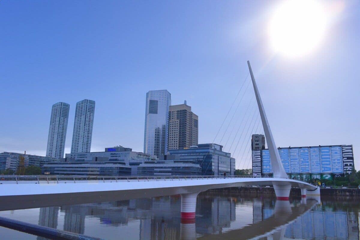 Un puente moderno con diseño de cable, cielo despejado y rascacielos al fondo.