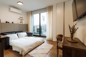 Een moderne slaapkamer met een bed, nachtkastje en een aan de muur bevestigde televisie.