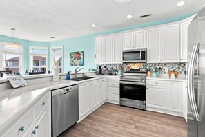 A modern kitchen with white cabinetry, a stainless steel refrigerator, a built-in oven, and a microwave. - Almost Heaven | Beachside Living, Ocean Breezes (North Topsail Beach)