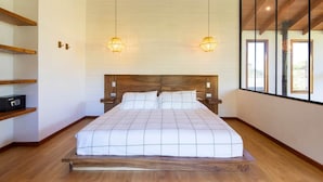 A bedroom with a wooden bed frame, a nightstand, a bedside table, and a built-in shelf. - Casa Jaguar Number 1 (Monteverde)