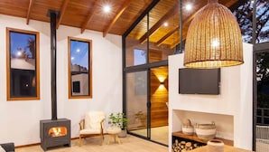 A modern living room with a large wooden table, a fireplace, and a hanging light fixture. - Casa Jaguar Number 1 (Monteverde)