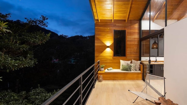 A modern interior with a wooden ceiling, a seating area with cushions, and a large window. - Casa Jaguar Number 1 (Monteverde)