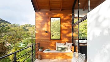 Un área de estar moderna al aire libre con techo de madera, vista del paisaje circundante y pared de vidrio.