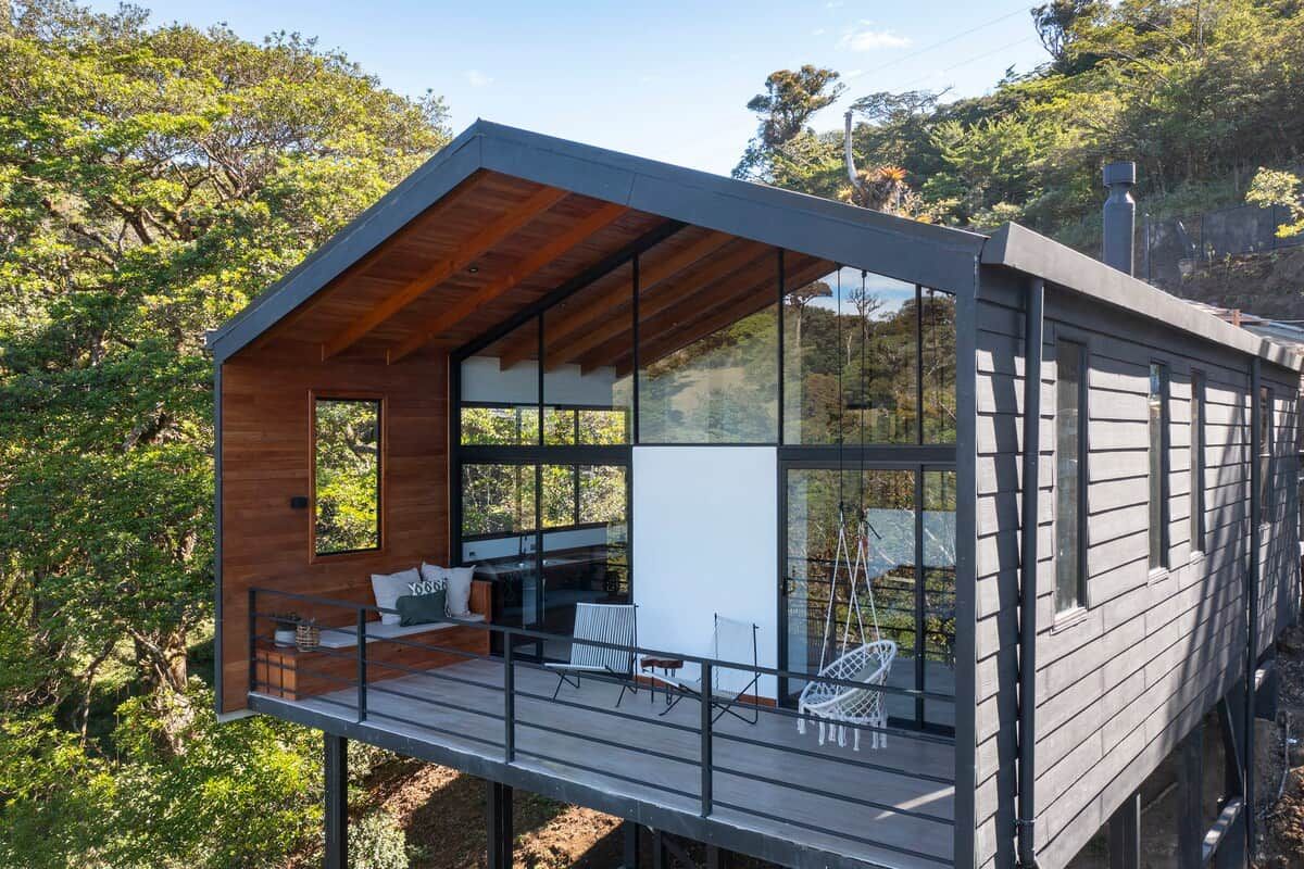 Una casa moderna con una terrazza in legno, ampie finestre e un balcone.