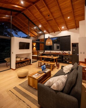 Una sala de estar moderna con un sofá grande, una mesa de centro y una zona de comedor con muebles de madera.