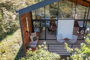 Ein modernes Haus mit Glasfassade, einer Holzdiele und einem Sitzbereich im Freien.