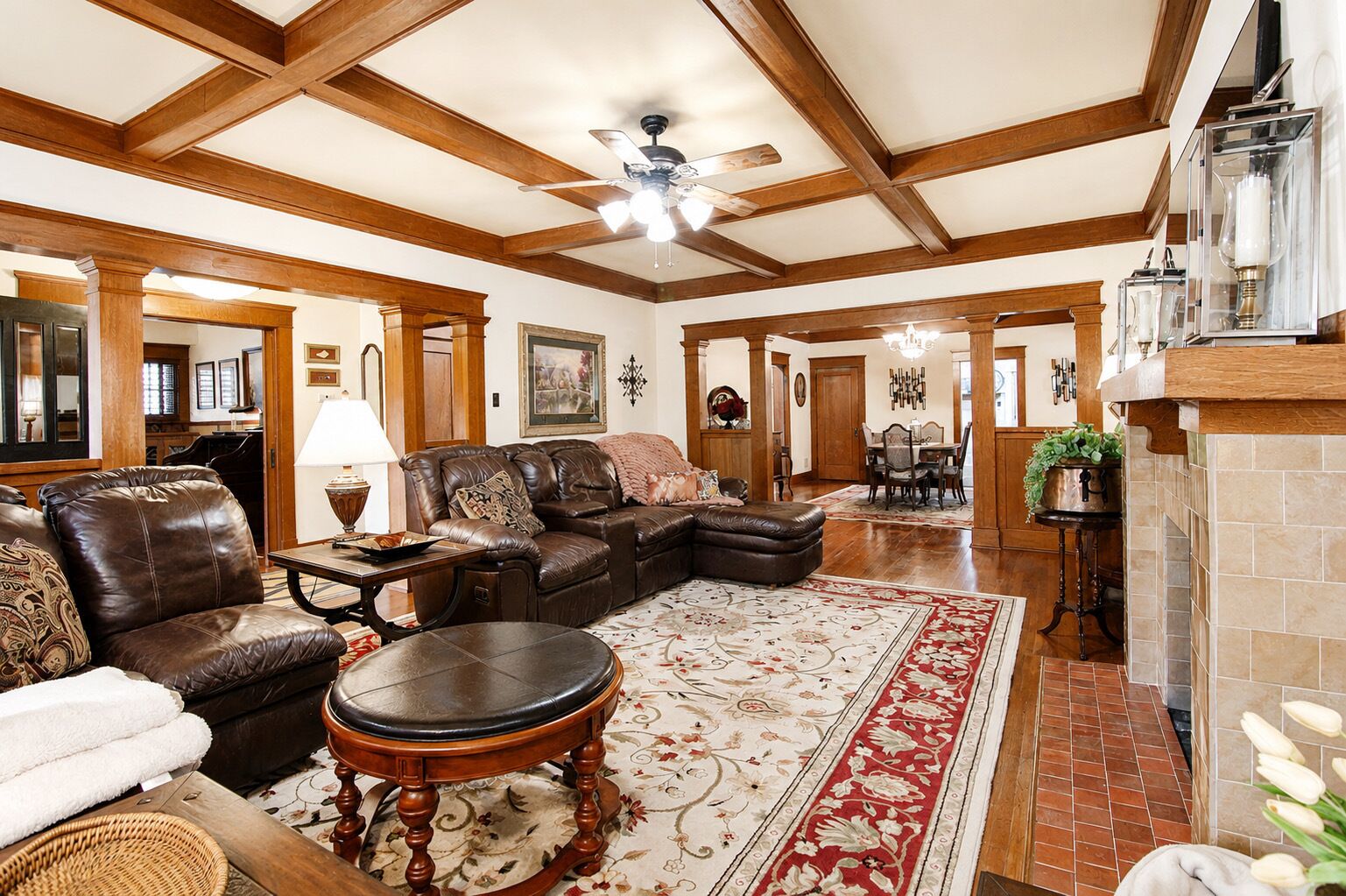 A spacious living room with a leather sofa, a round coffee table, and a fireplace.