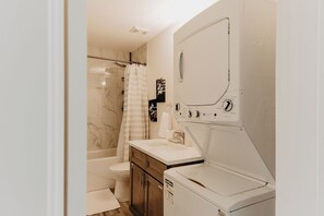 Een kleine badkamer met een douche, toilet en een geïntegreerde was-droogcombinatie.