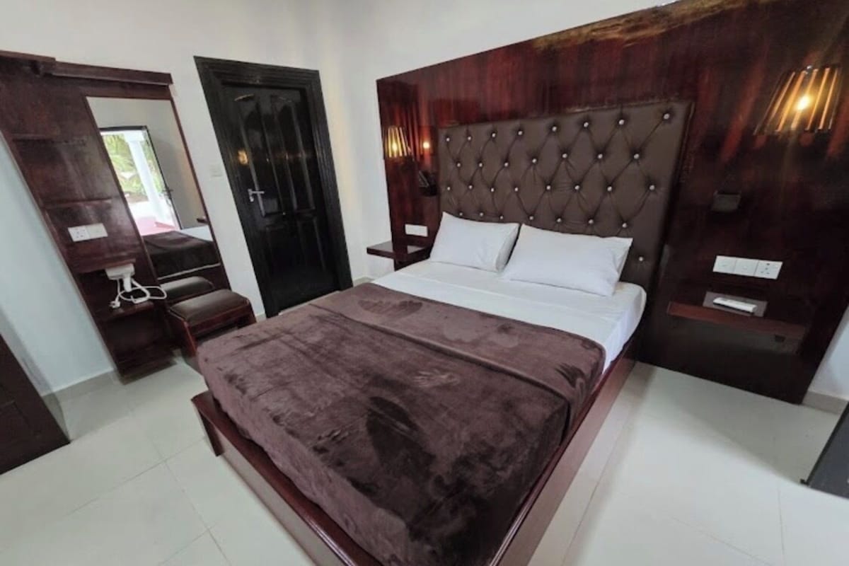 Un dormitorio con una cama grande, un cabecero de madera, una mesita de noche y un armario.