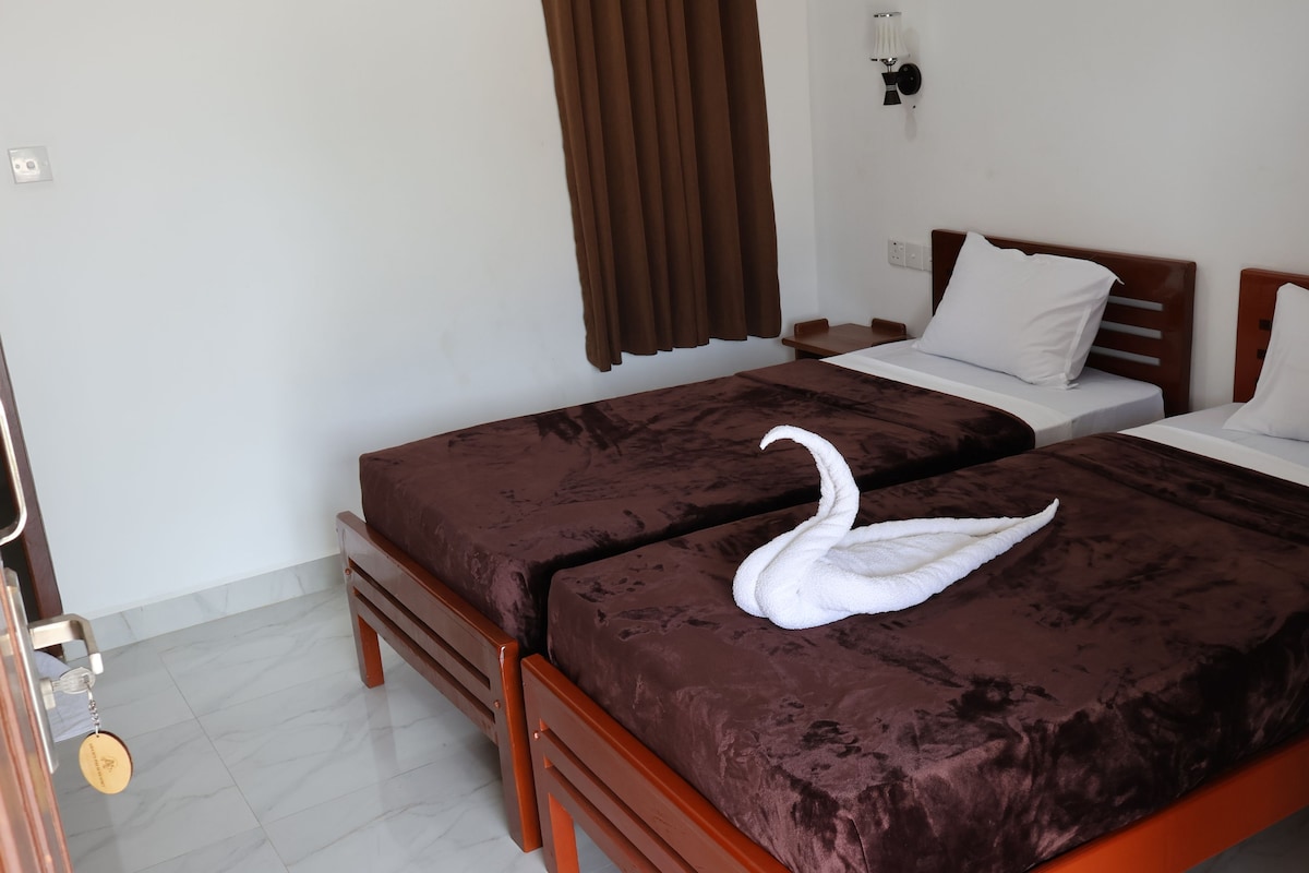Habitación de hotel con dos camas, una cortina marrón, una lámpara de pared y un llavero en la puerta.