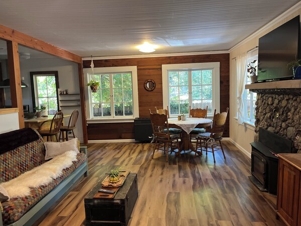 A cozy living room with a fireplace, wooden floors, a dining area, and a sofa.