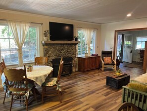 A cozy living room with a fireplace, wooden furniture, and a television mounted above it.