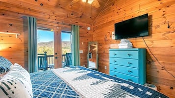 Een houten slaapkamer met een bed, een dressoir, een televisie en een balkon met uitzicht.