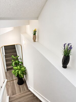 Ein modernes Interieur mit einer Treppe, weißen Wänden und zwei Blumentöpfen.