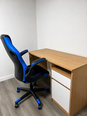 Ein Büro mit Ecke, ausgestattet mit einem Holztisch und einem schwarzen und blauen Bürostuhl.