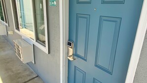 Eine blaue Tür mit Zahlenschloss, ein Fenster mit Blick auf einen Pool und ein Schild mit der Nummer 404 an der Wand.
