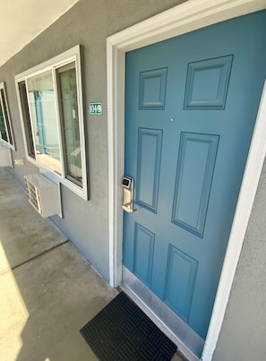 Una puerta azul con cerradura electrónica, una ventana con vista a una piscina y un letrero con el número '404' en la pared.