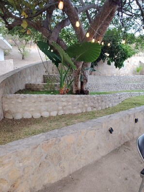 A stone retaining wall with a tree and string lights. - Designer Cabin with a Fire Pit and Magical Nights (Coxcatlán)