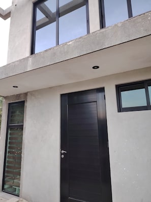 A modern building with a concrete facade, large windows, and a prominent black door.