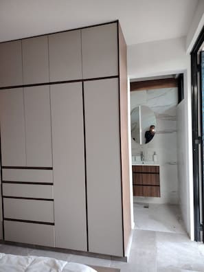 A modern bedroom with a large wardrobe, a bathroom with a marble vanity, and a large mirror.