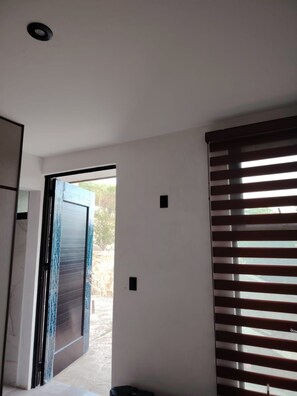 A room with a sliding door leading to an outdoor area, a window with horizontal blinds, and a small wall-mounted light fixture.