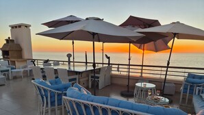 A terrace with wicker furniture, umbrellas, and a view of the sea at sunset. - Best Sea View in Morocco, Wheelchair Friendly, Plage des Nations, Rabat, Kénitra (Plage des Nations)