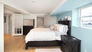 A bedroom with a large bed, a dresser, a vanity, and a window with a view. - "Church On The Lake", - Beaches, Beaches and more Beaches. Discover them All! (Lowbanks)