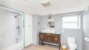 A bathroom with a walk-in shower, a vanity with a mirror, a toilet, and a window. - "Church On The Lake", - Beaches, Beaches and more Beaches. Discover them All! (Lowbanks)