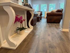 A living room with a white console table, a potted orchid, and a brown leather sofa. - Little oasis in Uptown San Antonio pool & jacuzzi (San Antonio)