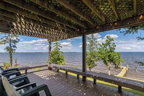 A wooden deck with chairs, a pergola, and a view of a lake. - Secluded Riverfront Estate with 180 Degree views-Hot Tub, Fire Pit, Kayaks (New Bern)