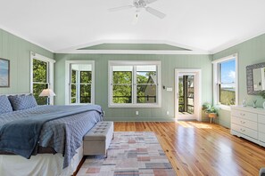 A bedroom with a bed, a bench, a dresser, and a large window. - Secluded Riverfront Estate with 180 Degree views-Hot Tub, Fire Pit, Kayaks (New Bern)