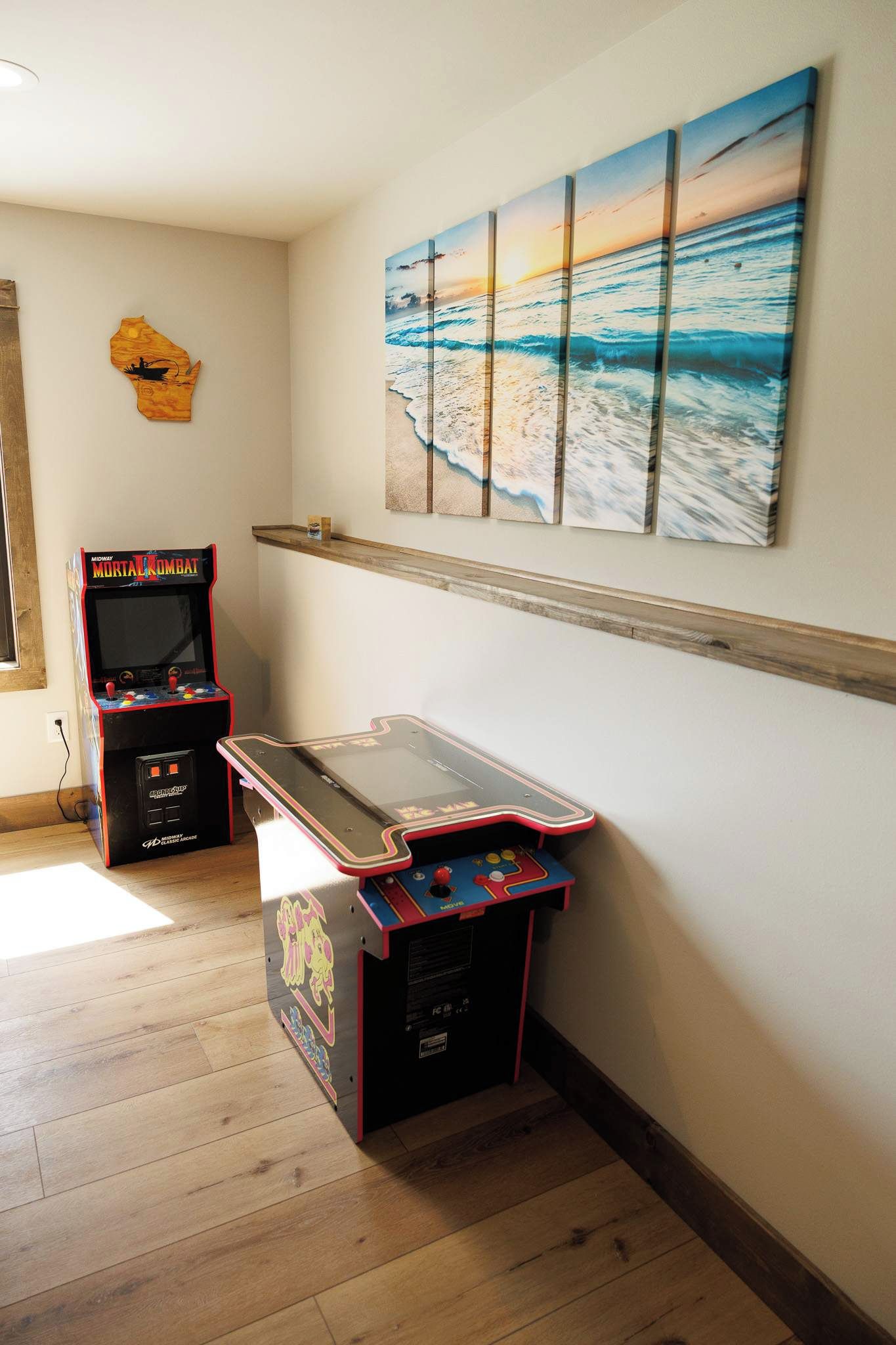 Une pièce dotée d’un plancher en bois, d’une table de billard et de jeux d’arcade.