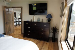 Ein Schlafzimmer mit Bett, Kommode, Fernseher und Fenster.