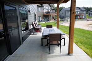 An outdoor patio with a table and chairs, a covered seating area, and a view of neighboring houses. - Rustic Retreat | Fall Lake Retreat | Fire Pit, Kayaks & Paddleboards (New Lisbon)