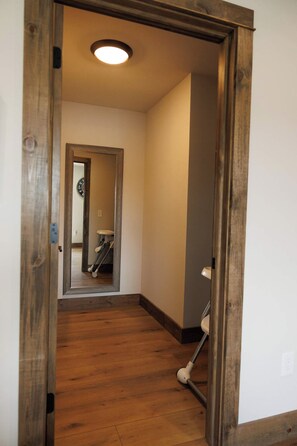 Ein Flur mit Holzboden, einer Tür zu einem Badezimmer und einer sichtbaren Toilette.