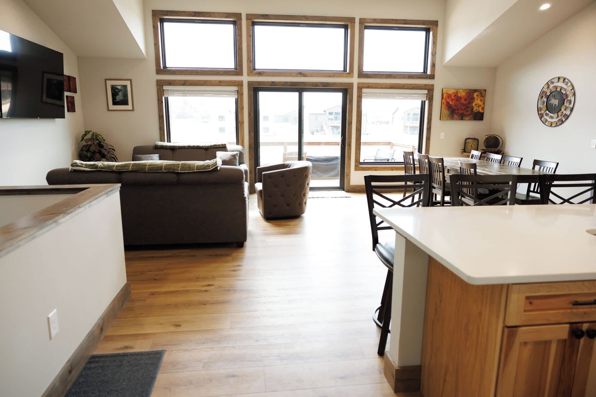 Eine moderne Küche mit Holzausstattung, ein Essbereich mit Tisch und Stühlen sowie ein Wohnzimmer mit Sofa und Couchtisch.