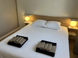 A neatly made bed with two pillows, two bedside lamps, and folded towels on the bed. - At Germaine: Air-Conditioned Apartment with Ocean View (Six-Fours-les-Plages)