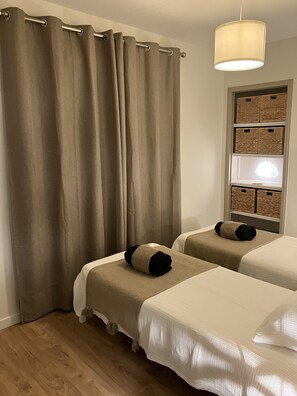 A hotel room with two beds, beige curtains, a hanging light fixture, and storage baskets on a wall. - At Germaine's: Air-conditioned apartment with a view of the sea (Six-Fours-les-Plages)