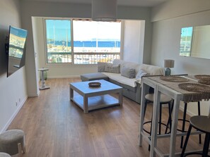A modern living room with a sofa, coffee table, and a dining area with a table and chairs. - At Germaine's: Air-conditioned apartment with a view of the sea (Six-Fours-les-Plages)